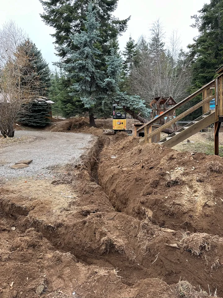 Mini excavator digging and shaping a new pond on a rural lot